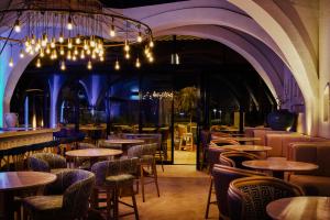 ein Restaurant mit Tischen, Stühlen und einem Kronleuchter in der Unterkunft The OQ in Doha