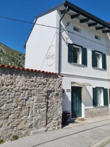 a white building with a stone wall at Rozalija house - Počitniška hiša z vrtom ob reki Soči v Solkanu in Solkan