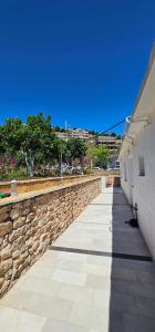 a stone wall next to a sidewalk next to a building at Loft Apartments in Sarandë