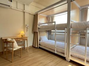 2 Etagenbetten in einem Zimmer mit einem Schreibtisch und einem Stuhl in der Unterkunft Ease at Sathorn Hostel and Coworking Space in Bangkok