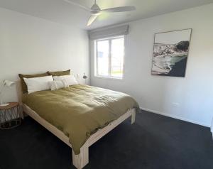 a bedroom with a large bed with a window at Palm Retreat - Whitianga in Whitianga