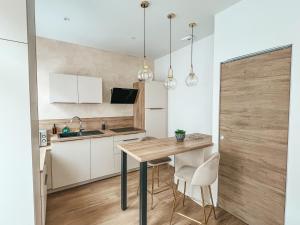une cuisine avec une table en bois et des armoires blanches dans l'établissement T2 centre ville de Perros Guirec, à Perros-Guirec