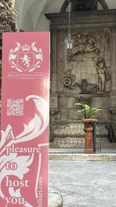 un cartello rosa davanti a un edificio con un muro di Palazzo Santa Ninfa - Luxury Mansion a Palermo