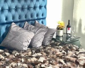 a bed with a blue headboard and a table with wine bottles at Cosmopolitan am Schlosspark in Paderborn
