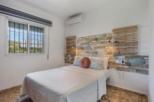 a bedroom with a bed and a brick wall at Chalet Novo Sancti Petri Surf in Chiclana de la Frontera
