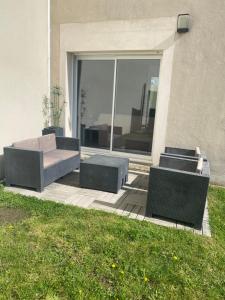 a patio with a couch and chairs in front of a building at Maison proche de l'aéroport et Nantes in Rezé