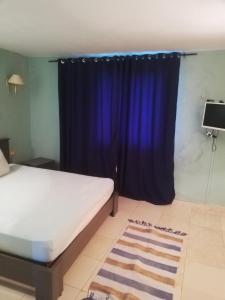 a bedroom with a bed and a blue curtain at Villa habiba 3 chambres in El Haouaria