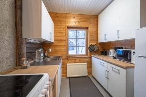 a kitchen with white appliances and wooden walls at Kuukkeli Log Houses Aurora Cabin - Jaspis in Saariselka