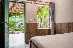 a bedroom with a bed and a sliding glass door at Greenfield Farmstay Vung Tau in Ba Ria