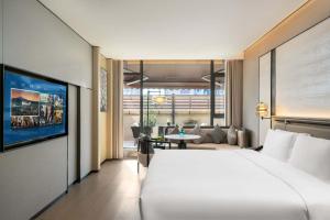 Un dormitorio con una cama grande y una sala de estar. en 上海虹桥荷逸唐酒店北新泾地铁站Shanghai Hongqiao Heyitang Hotel Beixinjing Subway Station Branch, en Shanghái
