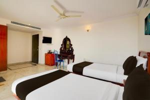 a bedroom with two beds and a ceiling fan at Super Townhouse Civil Aviation HAL Road in Bengaluru +25 photos