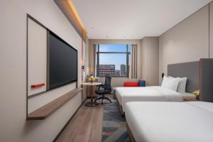 a hotel room with two beds and a flat screen tv at Holiday Inn Express Qingdao City Balcony by IHG in Qingdao +57 photos