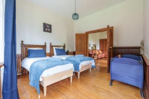 twee bedden in een kamer met blauwe lakens bij Gîte de l'Oriel - Gîte avec Grand Jardin in Sainte-Marie-aux-Mines