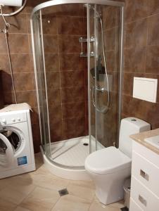 a bathroom with a shower with a toilet and a washing machine at NikeaPark in Golden Sands