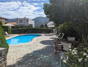 a swimming pool with chairs and a table next to a house at Guesthouse Christos in Skopelos Town