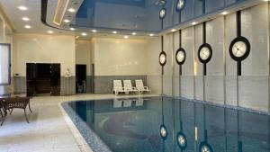 a swimming pool in a lobby with chairs and a table at Chinor Hotel Fergana in Fergana