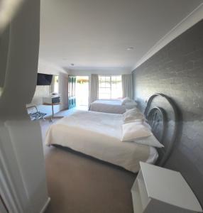 a bedroom with two beds and a brick wall at MOTEL ROYAL TARA in Binalong +49 photos