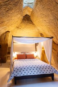 - une chambre en pierre avec un lit à baldaquin dans l'établissement La Petite Perrière Gite, à Doué-la-Fontaine