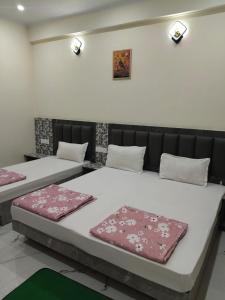 two beds in a room with two pillows on them at Hotel Dev Inn Ayodhya in Ayodhya