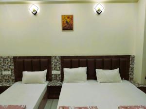 two beds sitting next to each other in a room at Hotel Dev Inn Ayodhya in Ayodhya