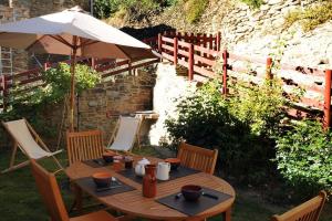 un tavolo di legno con un ombrellone e delle sedie di GITE MADRES- CORONAT BALCON du CANIGOU a Jujols