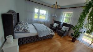 a bedroom with a bed and a chair and windows at Mazurskie Zacisze - sauna, jacuzzi, kominek in Trygort