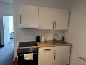 a kitchen with white cabinets and a stove and a sink at Zentrales Boardinghouse MG Rheydt in Mönchengladbach