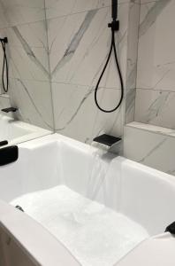 a white bathroom with a tub and a shower at City Central Esztergom in Esztergom