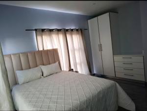 a bedroom with a large bed and a dresser at Melz & Sno Apartments in Mbabane