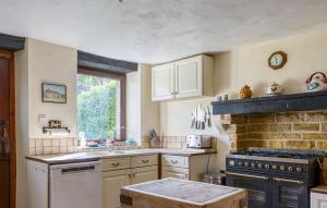 a kitchen with white appliances and a brick wall at Charmante Maison Avec Piscine in Lizant