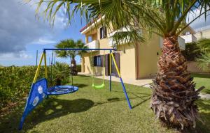 a swing set in a yard next to a palm tree at L'onda Dolce in Diamante +12 photos