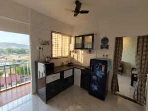a kitchen with a refrigerator and a large window at Jyotirlinga Homestay in Trimbak