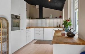 a kitchen with white cabinets and a wooden table at Cozy Home In Rønde With Wifi in Rønde +8 photos