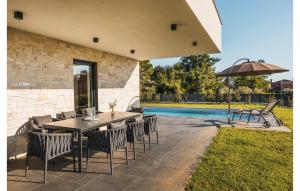 un patio avec une table, des chaises et un parasol dans l'établissement Cozy Home In Kastelir With Sauna, à Kaštelir 42 autres photos