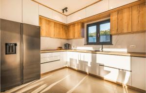 une cuisine avec des armoires en bois et un réfrigérateur en acier inoxydable dans l'établissement Cozy Home In Kastelir With Sauna, à Kaštelir