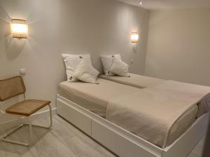 a bed with two pillows and a chair in a room at Beach House nr 69 in Ouddorp