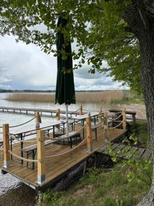 an umbrella sitting on a dock next to a lake at Mazurskie Zacisze - sauna, jacuzzi, kominek in Trygort +15 photos