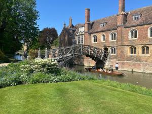 ein Boot, das unter einer Brücke vor einem Gebäude hindurchfährt in der Unterkunft The Jade House - Cambridge Rental with Garden and BBQ, Near City Centre in Cambridge