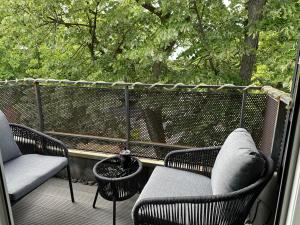 a balcony with two chairs and a table and a tree at Dachnest mit Charme in Marl
