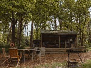 a cabin in the woods with a table and chairs at Moat Island Glamping in Norwich