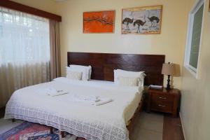 una camera da letto con un grande letto bianco con testiera in legno di DB Space a Nairobi