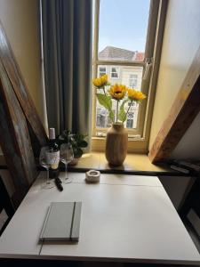 una mesa con un jarrón con flores en una ventana en The Hazel House, en Haarlem