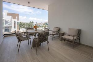 ein Esszimmer mit Tisch und Stühlen und einem großen Fenster in der Unterkunft Kalamon Luxury Suite 202 with Pool and Gym in Larnaka