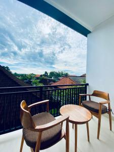 two chairs and a table on a balcony with a view at D'Tulak House in Ubud