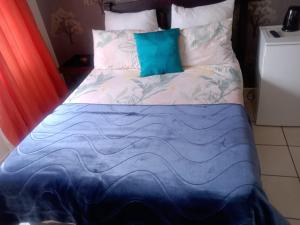a bed with a blue and white comforter on it at Nala Guesthouse in Ellisras