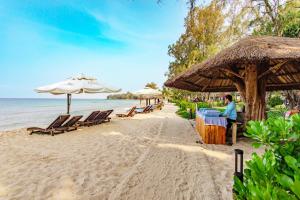 ein Strand mit Stühlen und Sonnenschirmen und das Meer in der Unterkunft Ocean Bay Resort & Spa Phu Quoc in Phu Quoc