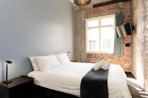 a bedroom with a large white bed with a window at Haka House Auckland K'Road in Auckland
