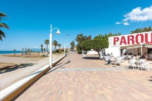 a sidewalk next to a beach with people sitting in chairs at La Casita De La Playa in Cala del Moral +13 photos