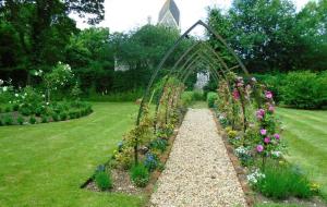 a garden with a arch and a bunch of flowers at The Old Coach House in Bungay