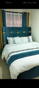a large bed with a blue headboard in a bedroom at Serenity in Ongata Rongai 